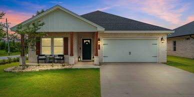 Modern single-story house with a landscaped front yard at sunset.