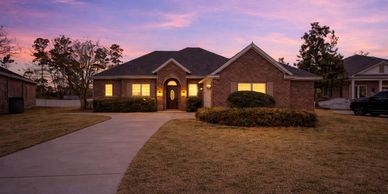 A cozy brick house with lit windows at twilight.