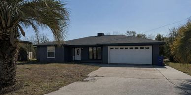 Single-story house with a two-car garage and a palm tree in the yard.