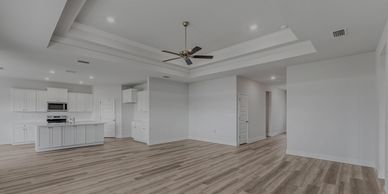 Spacious modern open-concept living room with white walls and wood flooring.