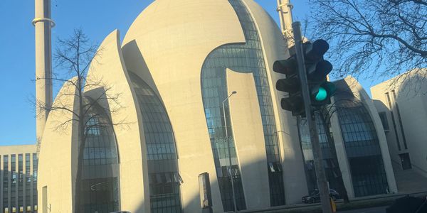 Modern mosque with a unique dome and minarets under clear blue sky.