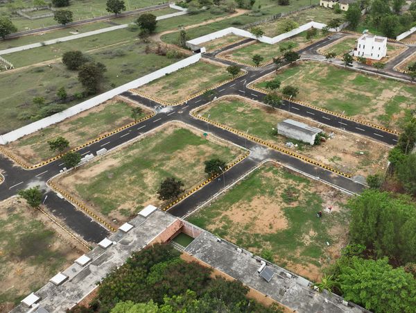 Aerial view of an empty housing plot layout with paved roads and greenery.