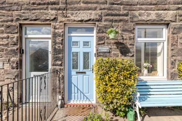 Stone house with blue door and bench outside.