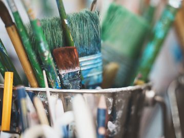 Close-up of paintbrushes and pencils in a container.