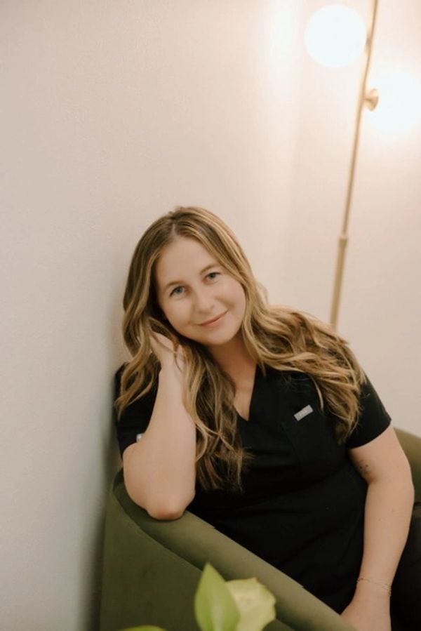 A woman with long hair smiling while sitting in a green chair.