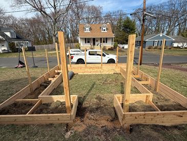 Partially constructed enclosed food garden with cedar posts and connecting planks.