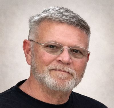 Portrait of an older man with glasses and a gray beard.