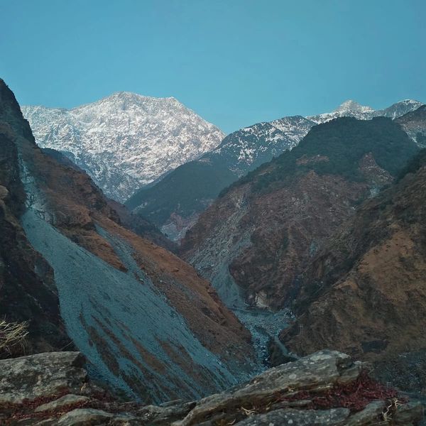 Snow-capped mountains towering over rocky valleys under a clear blue sky.
