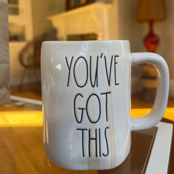 White mug with motivational text "YOU'VE GOT THIS" on a warm indoor table.