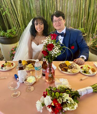 Smiling bride and groom at their wedding reception with celebratory meal.