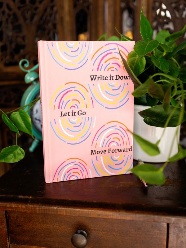 A pink notebook with motivational text on a wooden table.