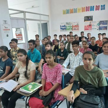 A classroom full of attentive students seated at desks with notebooks.