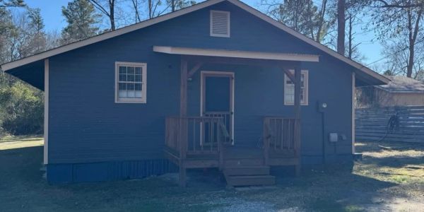Small blue house with a front porch and stairs.