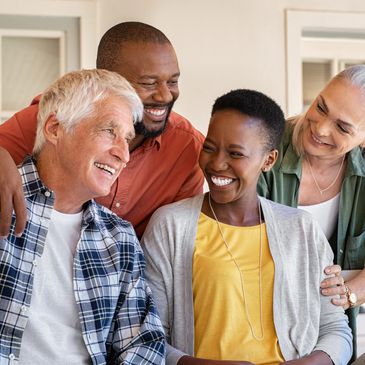 Four diverse adults happily engaging and smiling indoors.