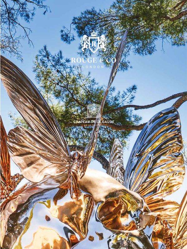 Shiny metallic butterfly sculptures reflecting sunlight under a clear blue sky.