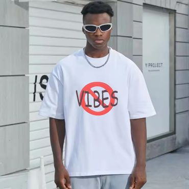 Young man wearing white sunglasses and a 'No Vibes' t-shirt.