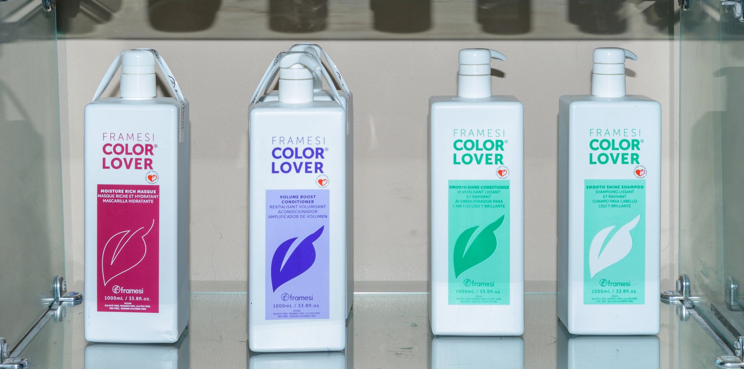Four Framesi Color Lover hair care products with different colored labels on a glass shelf.