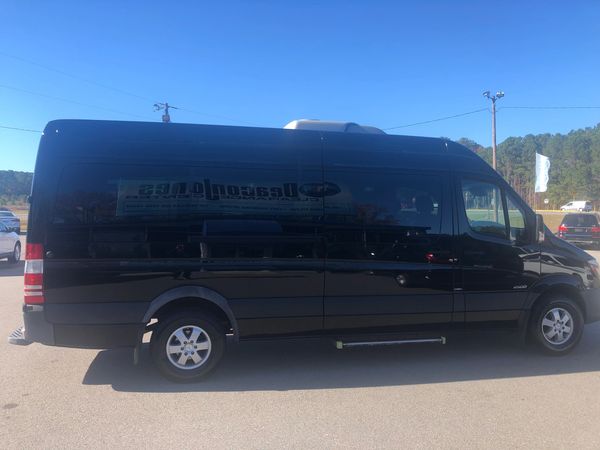 Black extended van parked on a sunny day in an open lot.