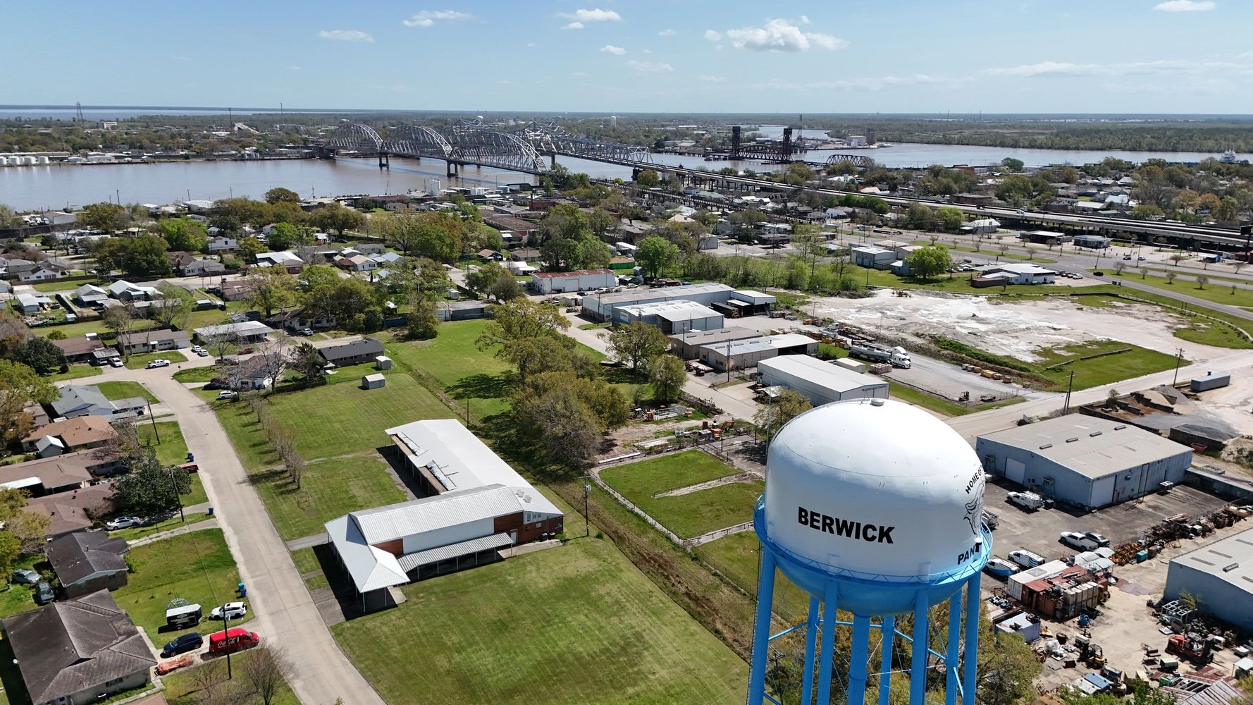 Aerial view of Berwick town with a water tower and river bridge in the background.
