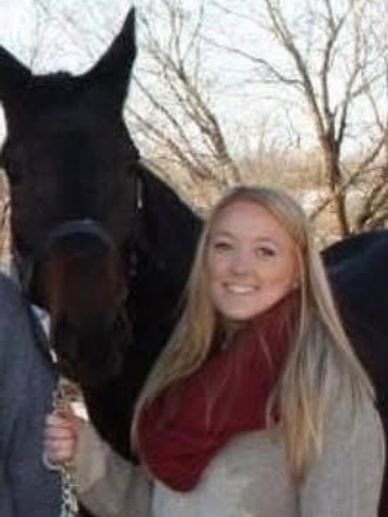 Woman smiling while holding a horse outdoors in winter.