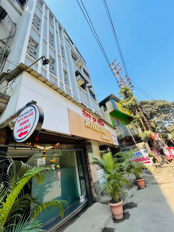 Facade of Royal Inn lodging with clear blue sky and potted plants outside.