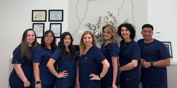 Dental team posing in front of Smiles on Olive sign.
