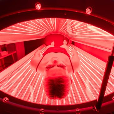 Person lying inside a red light therapy bed.
