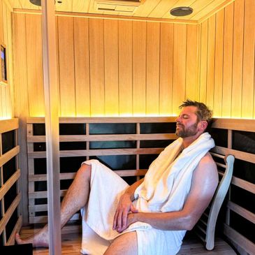 Man relaxing in a wooden sauna, wrapped in a towel.