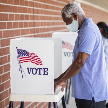 Man wearing mask casting vote at a polling station.