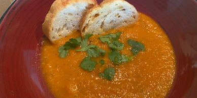 A bowl of creamy tomato soup garnished with fresh cilantro and two slices of toasted bread.