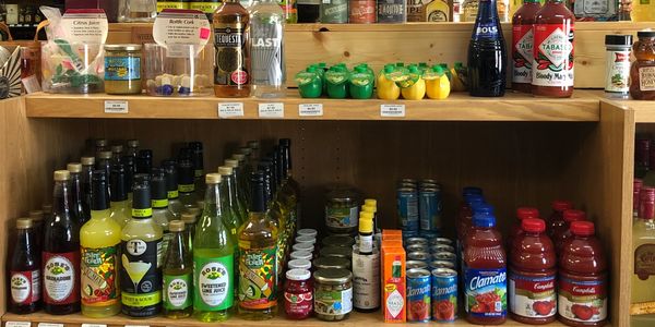 Shelf of drink mixers like lemon and tomato juice. Cherries, tobasco and bitters. 