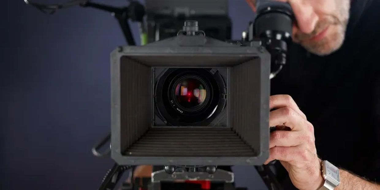 A person adjusting a professional video camera lens in a studio.