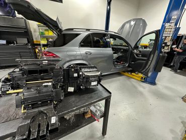 Car in a workshop with parts on a table.