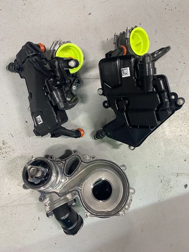 Three mechanical automotive parts on a gray surface.