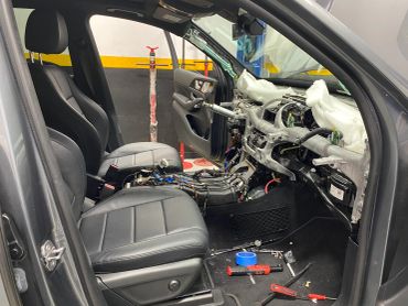 Car interior stripped down with exposed dashboard and tools scattered.