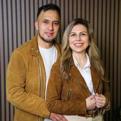 Couple wearing matching brown jackets posing and smiling together.