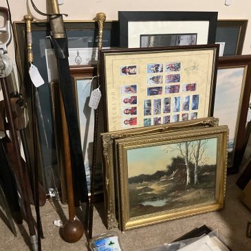 Collection of framed paintings, prints, and walking sticks.