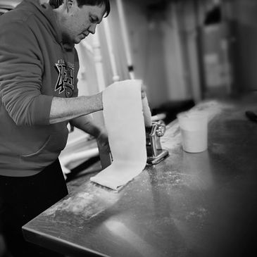 Image of our chef rolling pasta dough