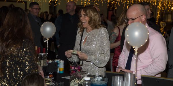 People enjoy a festive event with balloons and drinks at a decorated venue.
