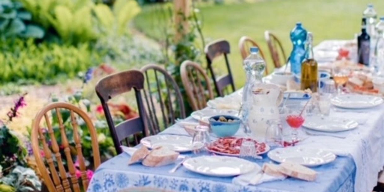 Outdoor table set for a meal with chairs and food.
