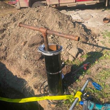 Excavated pipe installation with tools and caution tape.