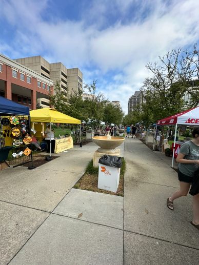 Outdoor market with tents and people on a sunny day.