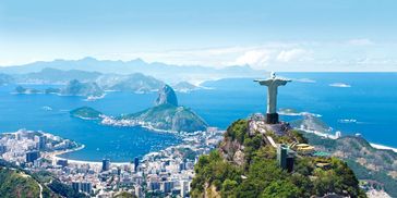 Panoramic view of Christ the Redeemer statue overlooking Rio de Janeiro's bay and mountains.