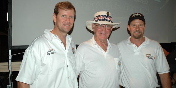 Three men in white shirts and hats are posing for a picture.