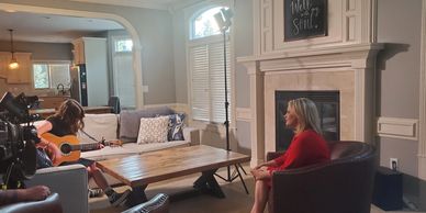 Woman in red shirt being interviewed in a living room.