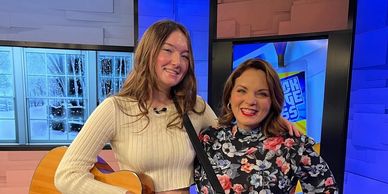 Two women smiling, one holding a guitar.