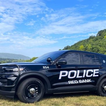 Black Red Bank police SUV parked on grass.
