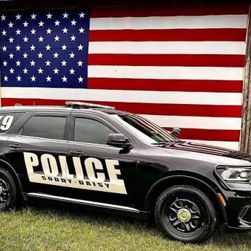 Police car parked in front of a large American flag.