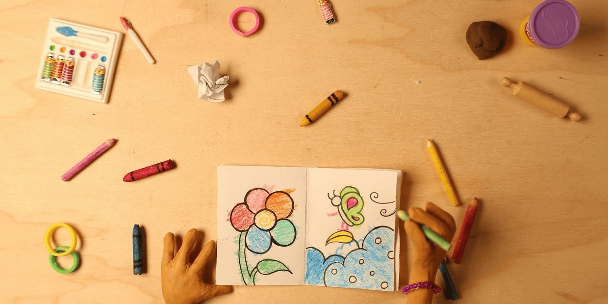 Clay hands drawing a colorful flower and butterfly.