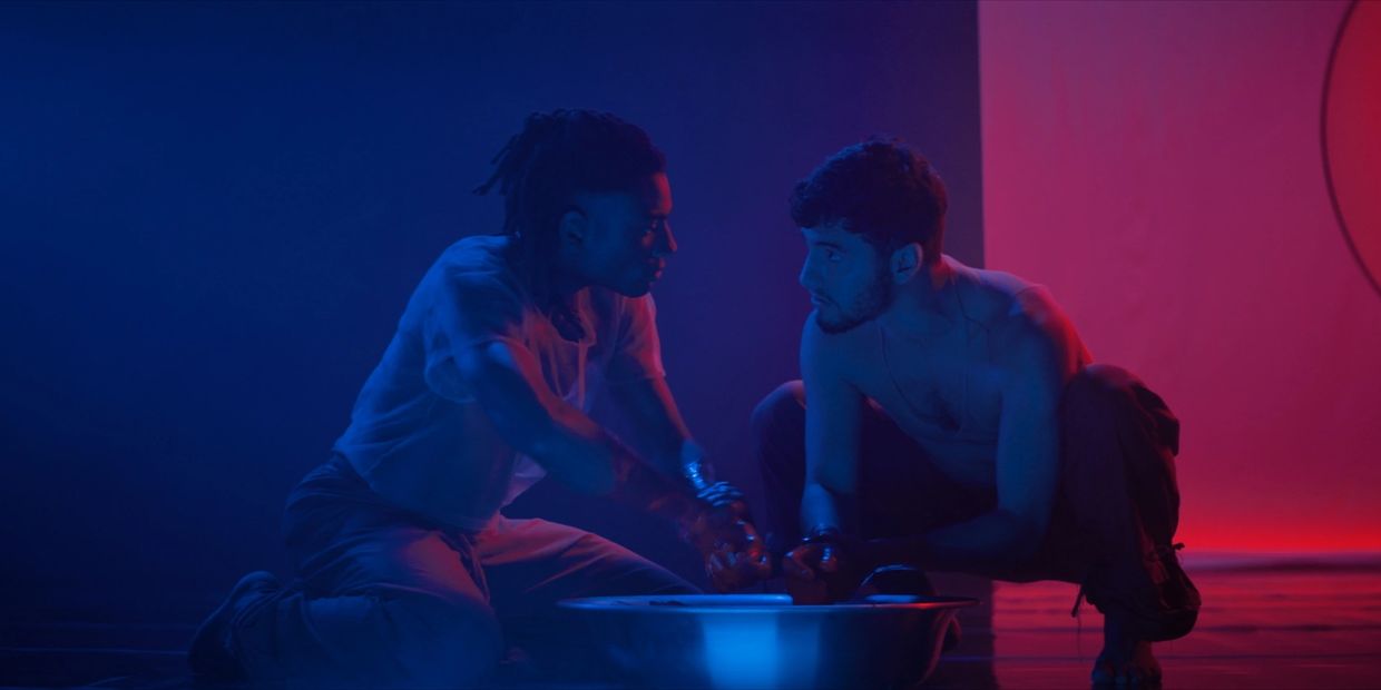 Two men facing each other in dramatic blue and red lighting.